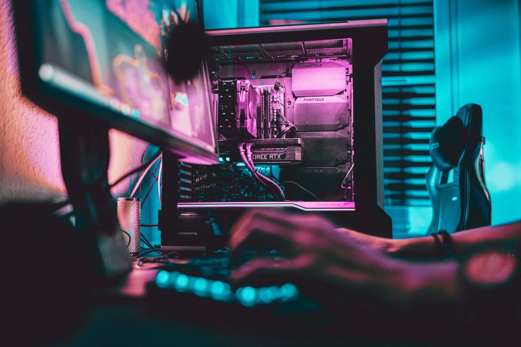 Gaming PC with RGB lighting and NVIDIA GeForce RTX graphics card in glass case with gamer at desk